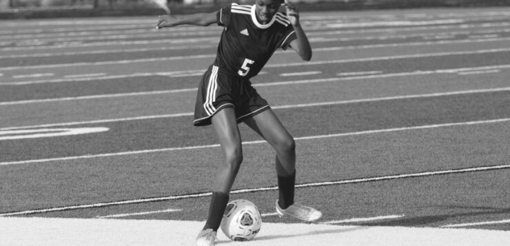 Greyscale photo of Black girl practising football